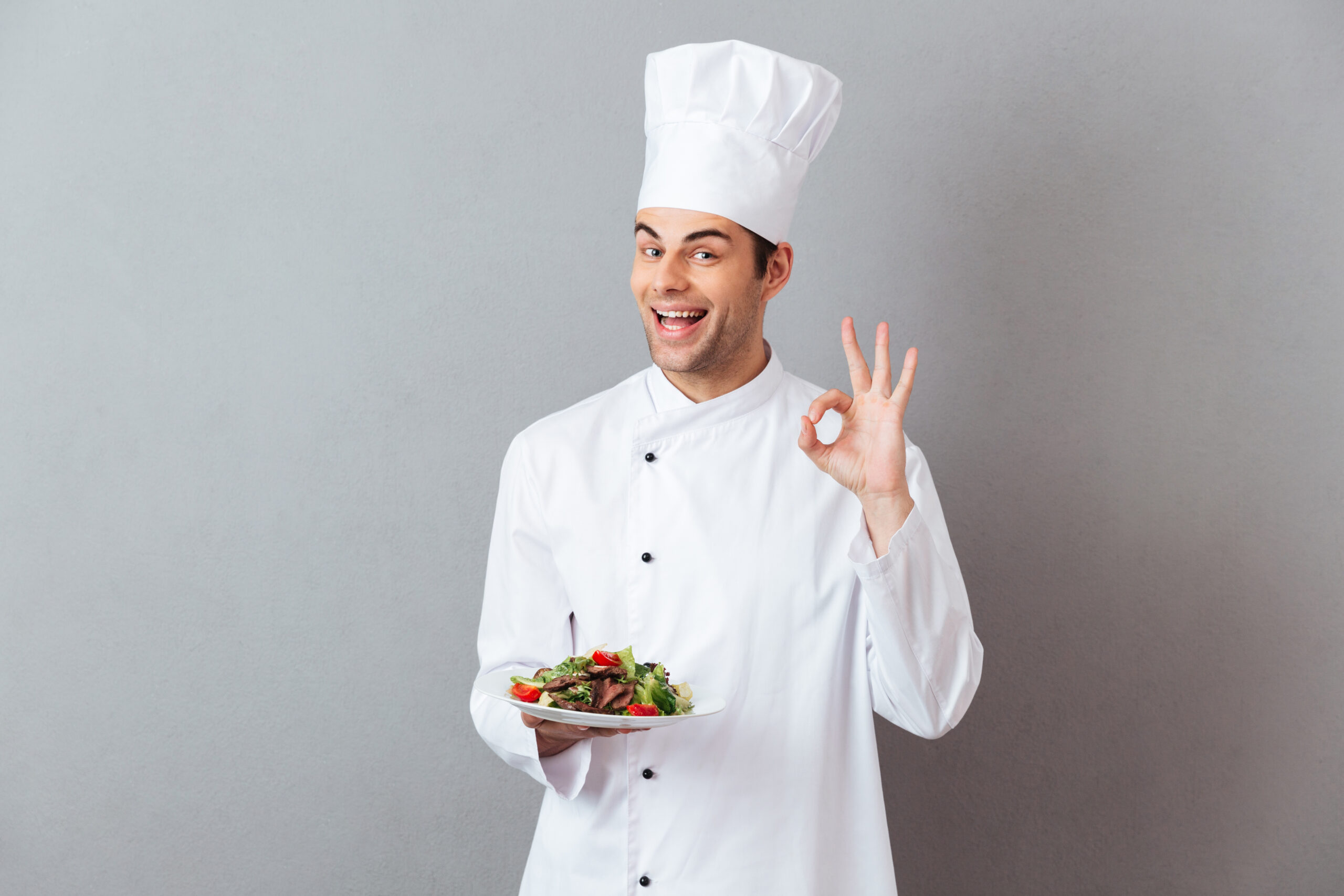 cook uniform holding salad showing okay gesture scaled
